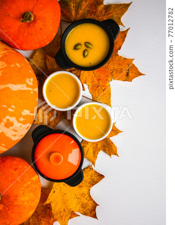 Autumn food. Pumpkin puree soup, leaves. Top view. Autumn harvest, pumpkins, leaves on grey as abstract background. Thanksgiving day. Flat lay. Autumn food. Pumpkin puree soup, leaves. Top view. Autumn harvest, pumpkins, leaves on grey as abstract background. Thanksgiving day. Flat lay. 77012782