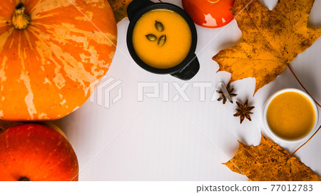 Autumn food. Frame of pumpkin puree soup, leaves. Top view. Autumn harvest, pumpkins, leaves on grey as abstract background. Thanksgiving day. Flat lay. Copy space Autumn food. Frame of pumpkin puree soup, leaves. Top view. Autumn harvest, pumpkins, leaves on grey as abstract background. Thanksgiving day. Flat lay. Copy space 77012783