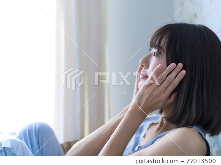 A woman touching her cheek 77013500