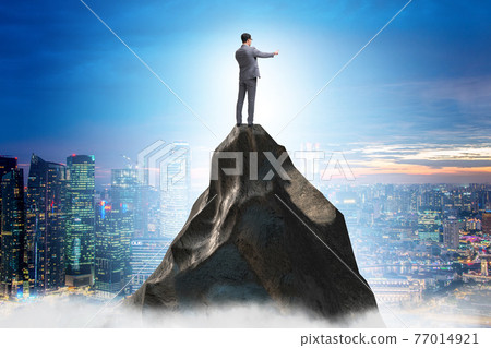 Businessman at the top of mountain in career concept 77014921