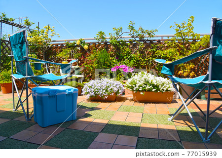 Outdoor chair & cooler box on the roof balcony, looking at the plants, relaxing time on holidays Outdoor chair & cooler box on the roof balcony, looking at the plants, relaxing time on holidays 77015939
