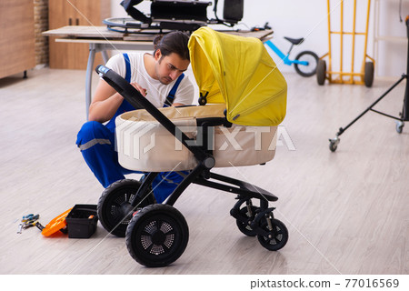 Young male repairer repairing perambulator indoors Young male repairer repairing perambulator indoors 77016569