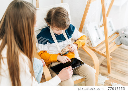 Mother with son in children's room, looking at tablet Mother with son in children's room, looking at tablet 77017353