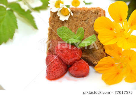 A piece of homemade coffee chiffon cake with edible flowers and strawberry jam A piece of homemade coffee chiffon cake with edible flowers and strawberry jam 77017573