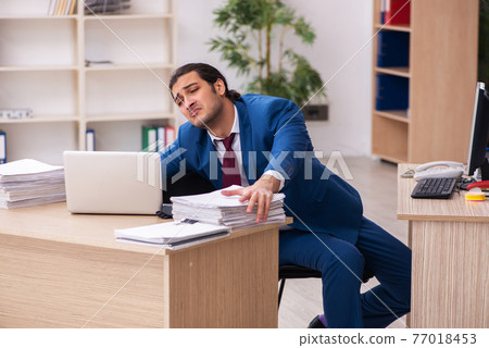 Young male employee in multitasking concept 77018453