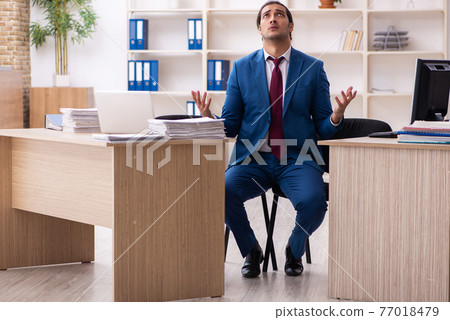 Young male employee in multitasking concept Young male employee in multitasking concept 77018479