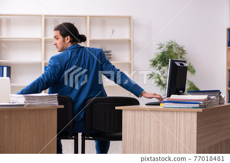 Young male employee in multitasking concept Young male employee in multitasking concept 77018481