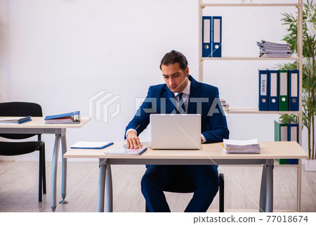 Young male employee working in the office Young male employee working in the office 77018674