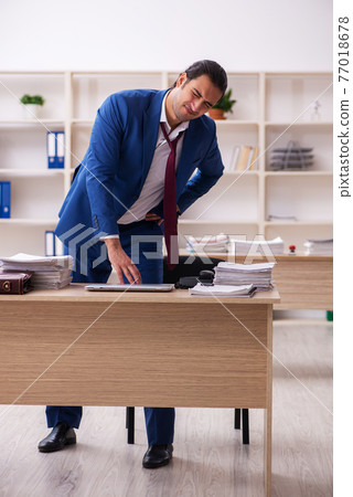 Young male employee doing sport exercises during break Young male employee doing sport exercises during break 77018678