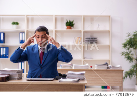 Extremely tired young male employee in the office Extremely tired young male employee in the office 77018679