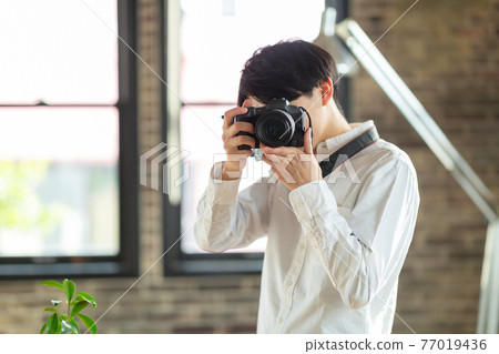 A man holding a camera 77019436