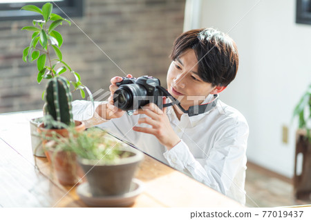 A man holding a camera 77019437