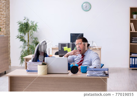 Young male employee in time management concept Young male employee in time management concept 77019855