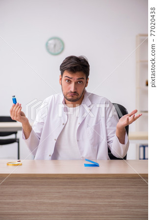 Young male chemist doctor holding vial 77020438