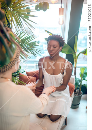 Dark-skinned woman visiting a doctor of alternative medicine 77021038