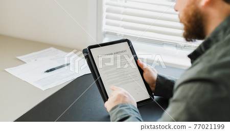 Man reading partnership agreement on tablet. Man reading partnership agreement on tablet. 77021199