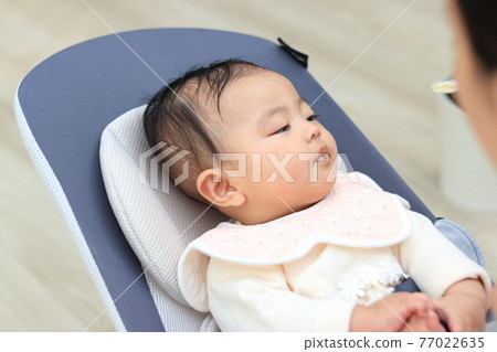 Baby feeding baby food in the living room Baby feeding baby food in the living room 77022635