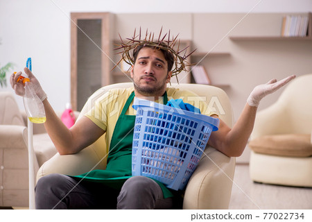 Young male contractor wearing prickly wreath on head cleaning th Young male contractor wearing prickly wreath on head cleaning th 77022734