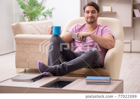 Young man drinking tea at home during pandemic Young man drinking tea at home during pandemic 77022899