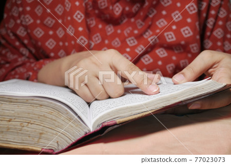 Muslim women's hand reading quran at night  77023073
