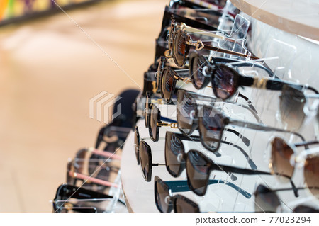 Sunglasses in the shop display shelves. Sunglasses in the shop display shelves. 77023294