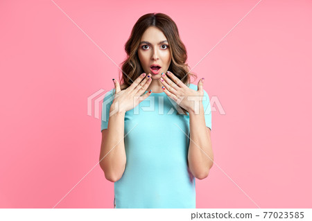 Portrait of a shocked surprised woman shouts on pink background. 77023585