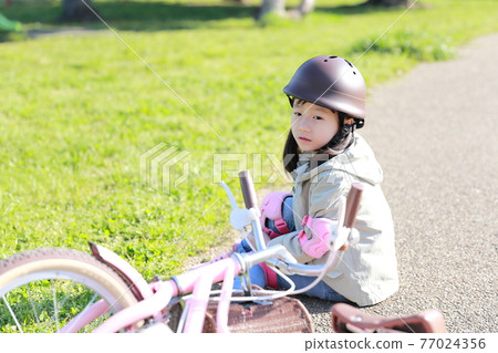 A girl who falls and gets injured while practicing a bicycle A girl who falls and gets injured while practicing a bicycle 77024356