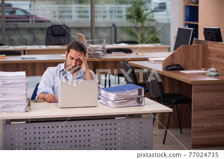 Young male employee working in the office Young male employee working in the office 77024735