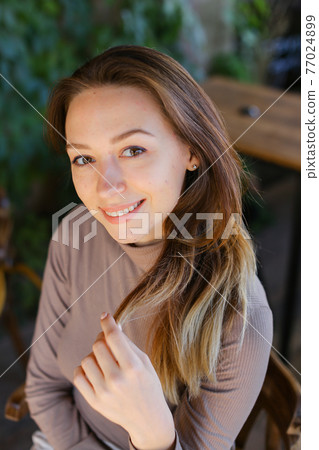 Young caucasian woman sitting on bench, portrait. 77024899
