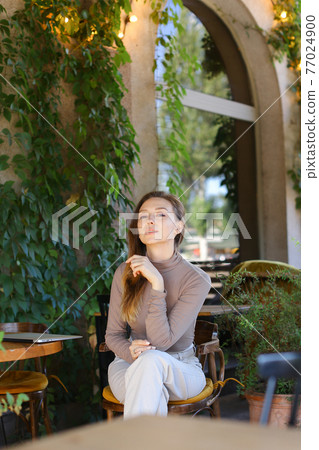 Young european woman posing at street cafe, closed laptop computer on table. Young european woman posing at street cafe, closed laptop computer on table. 77024900