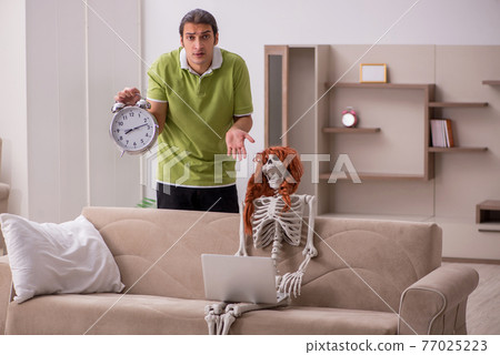 Young man with female skeleton in time management concept 77025223