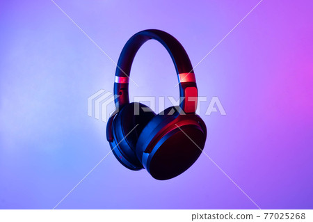 Black wireless bluetooth headphones on neon light background. Music concept. 77025268