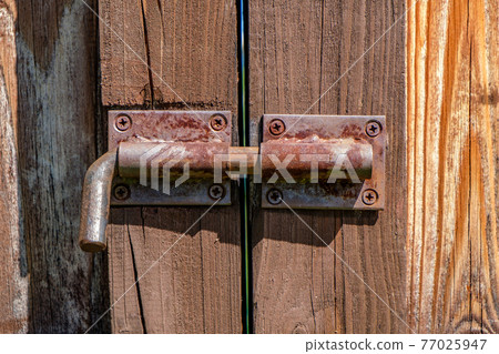 Metal latch on wooden gate closeup Metal latch on wooden gate closeup 77025947