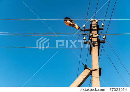 Electric pole and intersecting wires on a background of blue sky 77025954