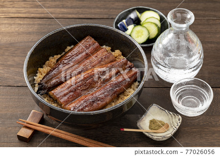 Unadon in a black bowl and sake placed on a wooden table Unadon in a black bowl and sake placed on a wooden table 77026056