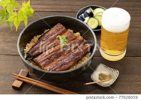 木紋桌上的黑碗烏冬面、啤酒、綠葉和樹芽 77026059