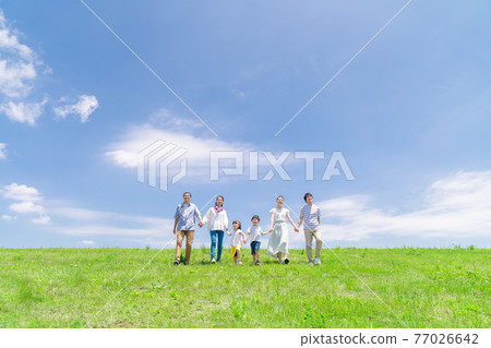 A three-generation family taking a walk under the blue sky 77026642