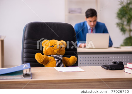 Young male employee and his toy bear boss in funny concept Young male employee and his toy bear boss in funny concept 77026730