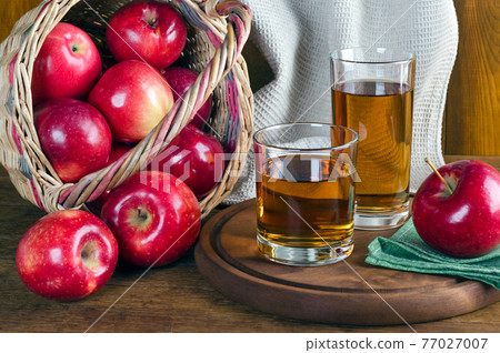Apple juice in glasses and apples in a basket. Apple juice in glasses and apples in a basket. 77027007