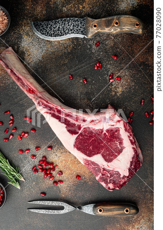 Cooking meat background. Raw tomahawk steak, with spices and herbs for cooking, with seasoning and herbs, on old dark rustic background Cooking meat background. Raw tomahawk steak, with spices and herbs for cooking, with seasoning and herbs, on old dark rustic background 77028090