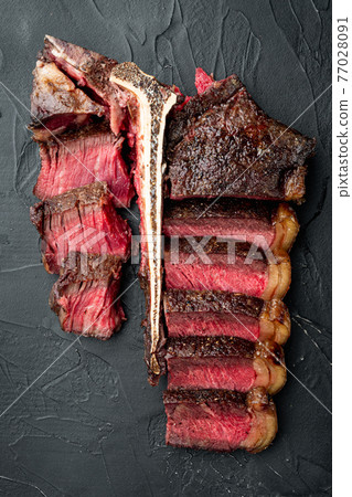 T bone steak is grilled sliced on a piece. Aged Barbecue Porterhouse Steak, on black stone background, top view flat lay 77028091