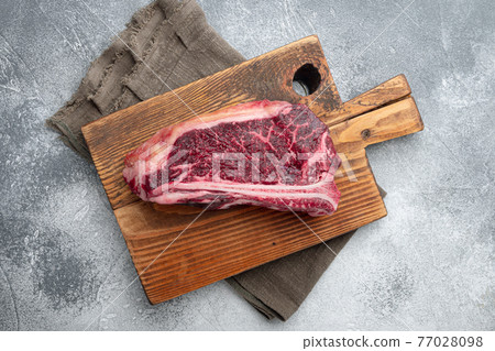 Raw fresh meat dry aged Club Steak, on gray stone background, top view flat lay Raw fresh meat dry aged Club Steak, on gray stone background, top view flat lay 77028098
