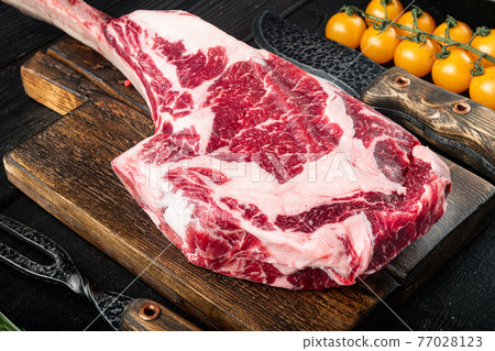 Barbecue Tomahawk marbled beef Steak, with grill ingredients, on black wooden table background Barbecue Tomahawk marbled beef Steak, with grill ingredients, on black wooden table background 77028123