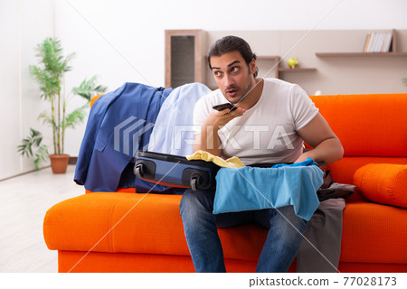 Young man student preparing for trip at home 77028173