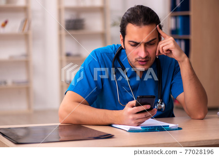 Young male doctor working in the clinic Young male doctor working in the clinic 77028196