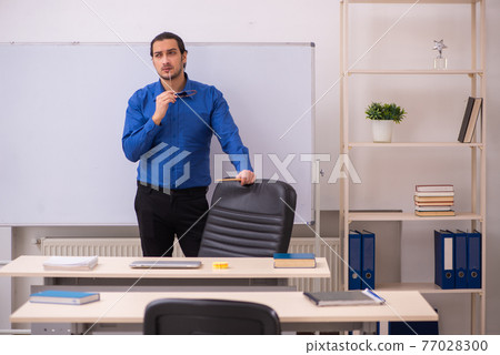Young male teacher in front of whiteboard Young male teacher in front of whiteboard 77028300