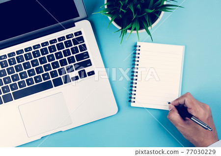 Flat lay, hand of businessman writing on notebook with Laptop computer and plant and pen. 77030229