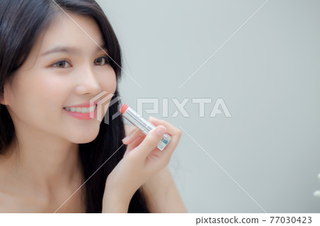 Beautiful young asian woman applying lipstick pink with style bright and shiny on mouth. Beautiful young asian woman applying lipstick pink with style bright and shiny on mouth. 77030423