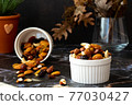 Mix of delicious assorted nuts and dried fruit in white cups on a table, sunny morning. Healthy gourmet vegetarian natural snack. 77030427