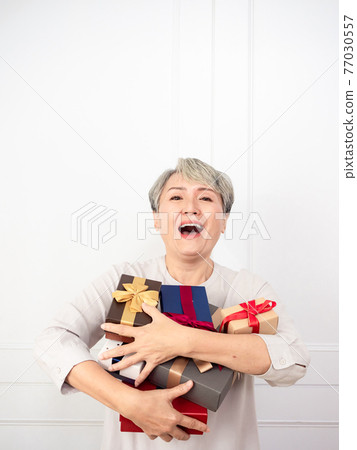 Senior asian woman holding mount of gift boxes, enjoying many best presents. 77030557